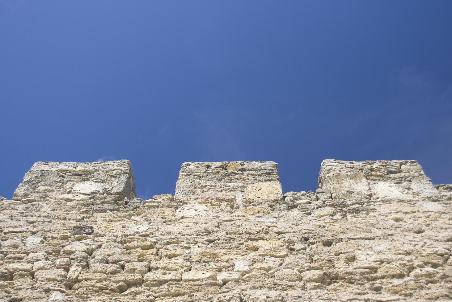 Merlons of an old fortress wall against blue sky photo
