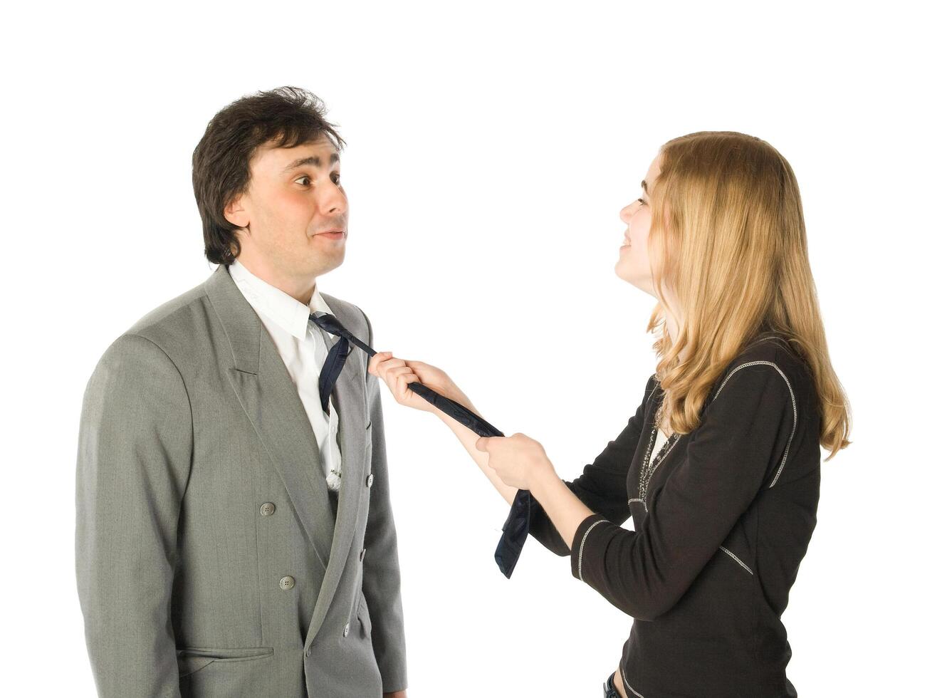 Young woman pulling a man by a necktie, isolated over white photo