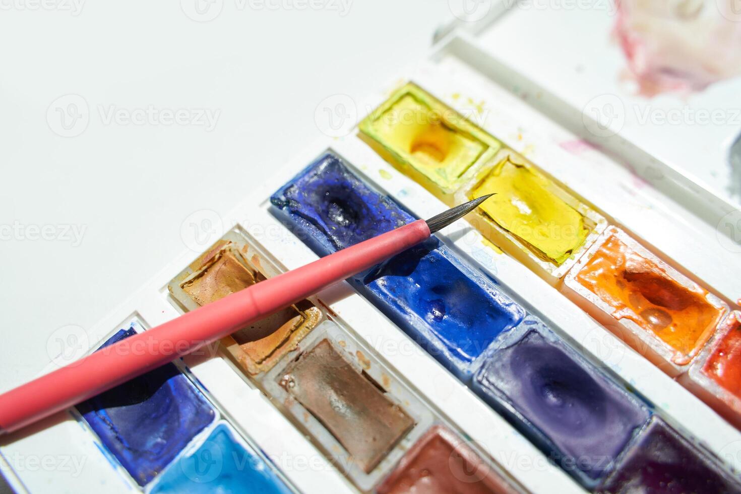 Colorful watercolor palette and brush on white table for artistic painting projects. photo