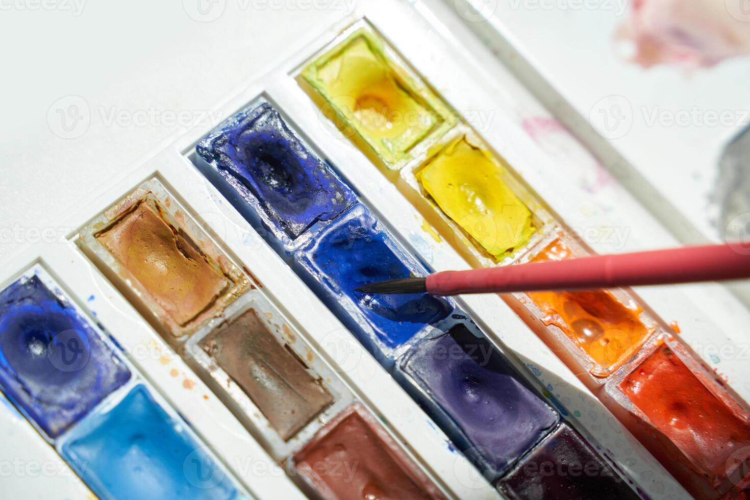 Watercolor palette with brush in blue paint and vibrant color choices for creative art projects. photo