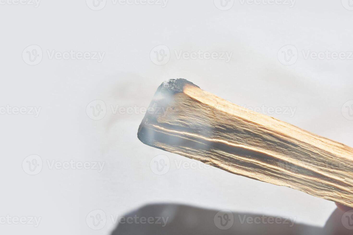 Close up of burning palo santo stick with smoke against white background. photo