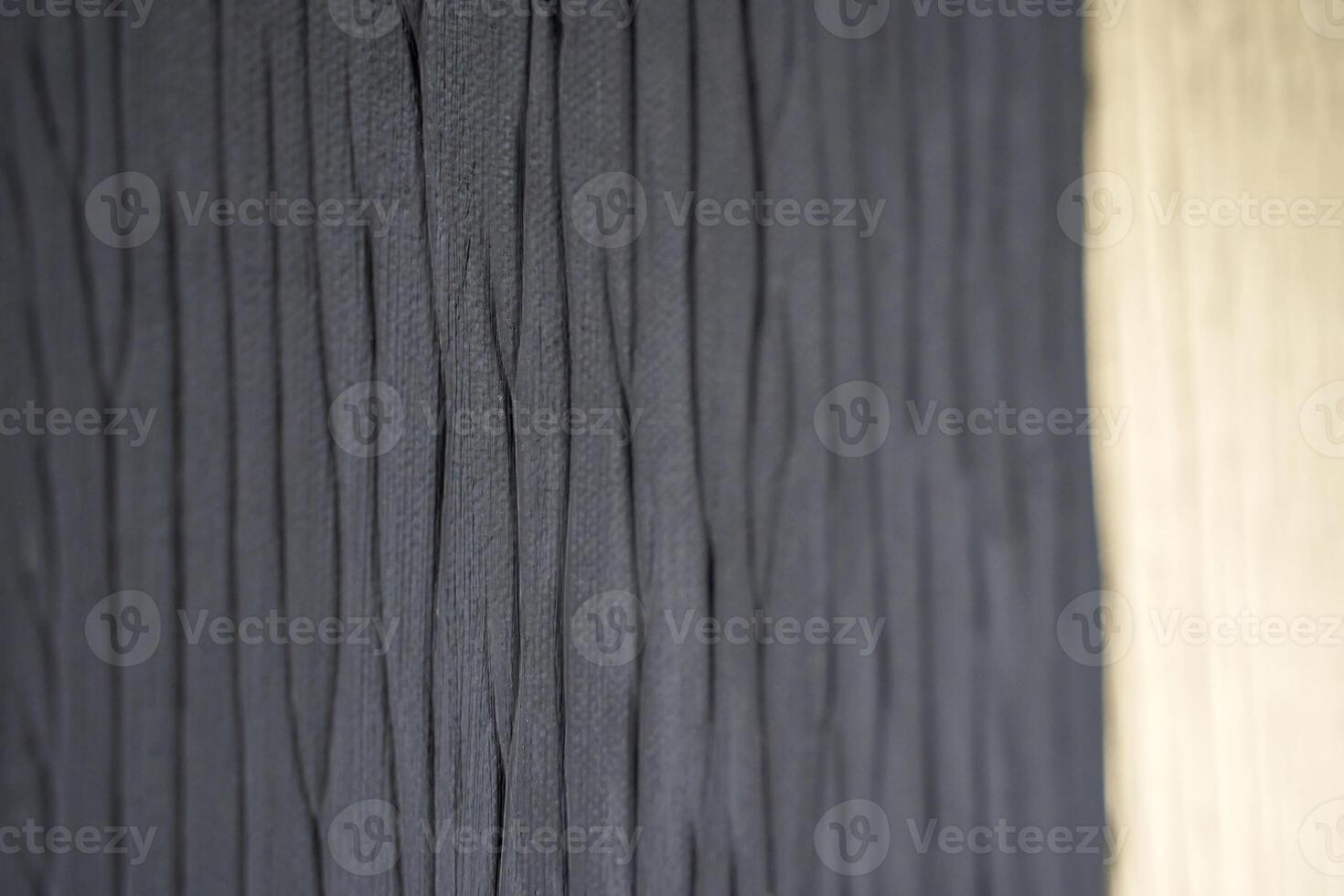 Close up of textured dark fabric with wavy pattern next to wooden surface. photo