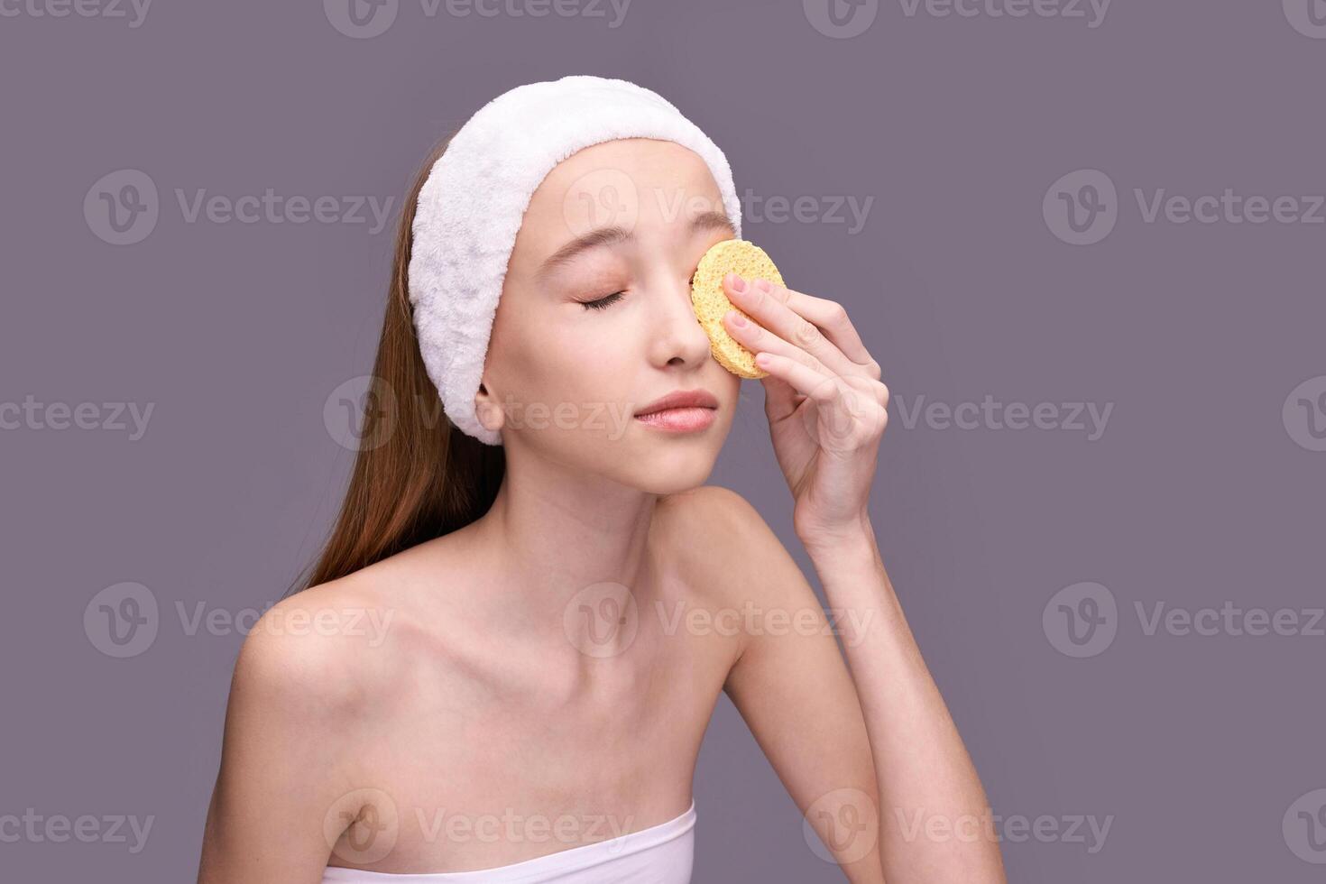 Young caucasian female applying skincare with sponge headband relaxation beauty routine. photo