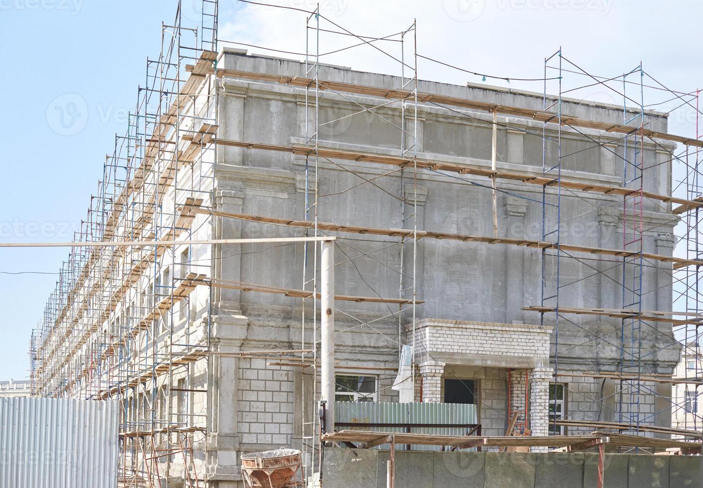 Large concrete building under construction with scaffolding and blue sky in background. photo