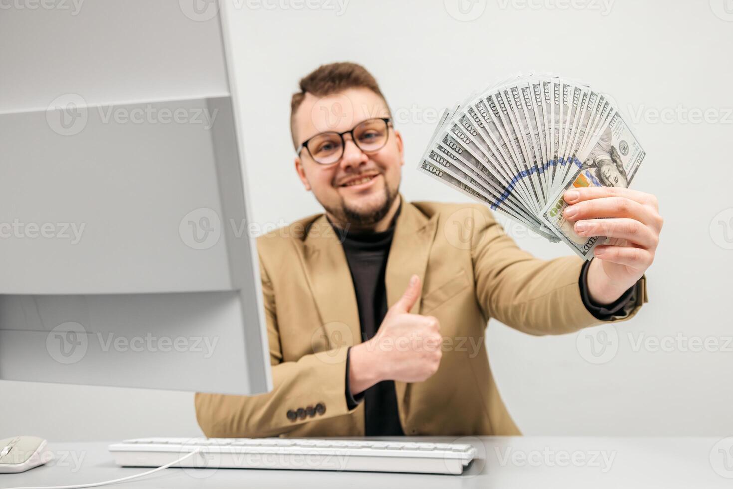 Happy businessman in glasses enjoys a large sum of cash in his hands in a modern office. The concept is to convey the feeling of achieving financial independence photo