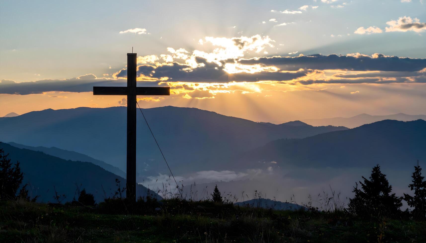 Silhouette of a wooden cross on a mountain during sunset with dramatic sky and sun rays. A powerful Christian symbol of faith. Perfect for ascension day jesus christ. photo