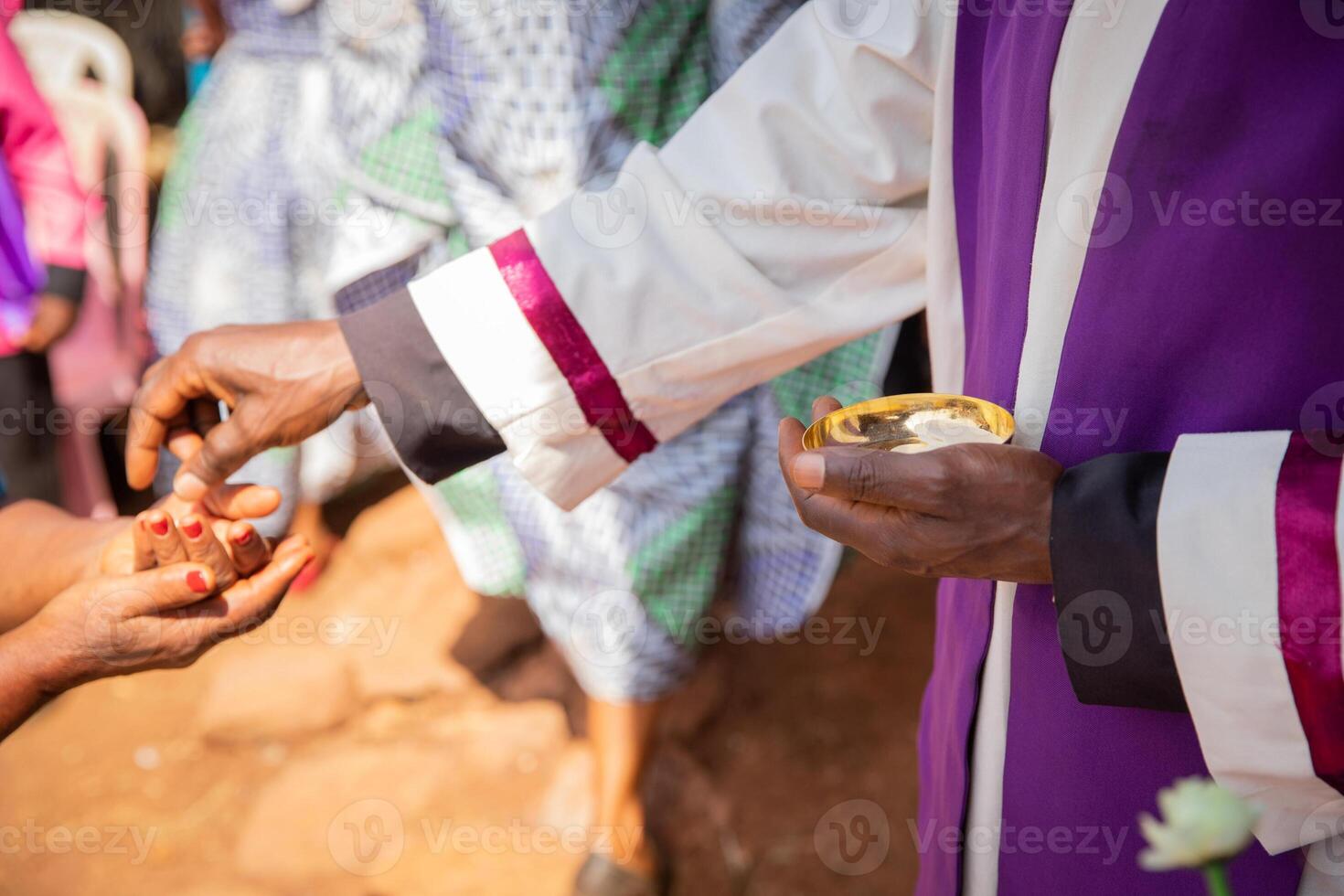 An African priest gives sacramental bread to a believer, focus on the hand with sacramental bread. photo