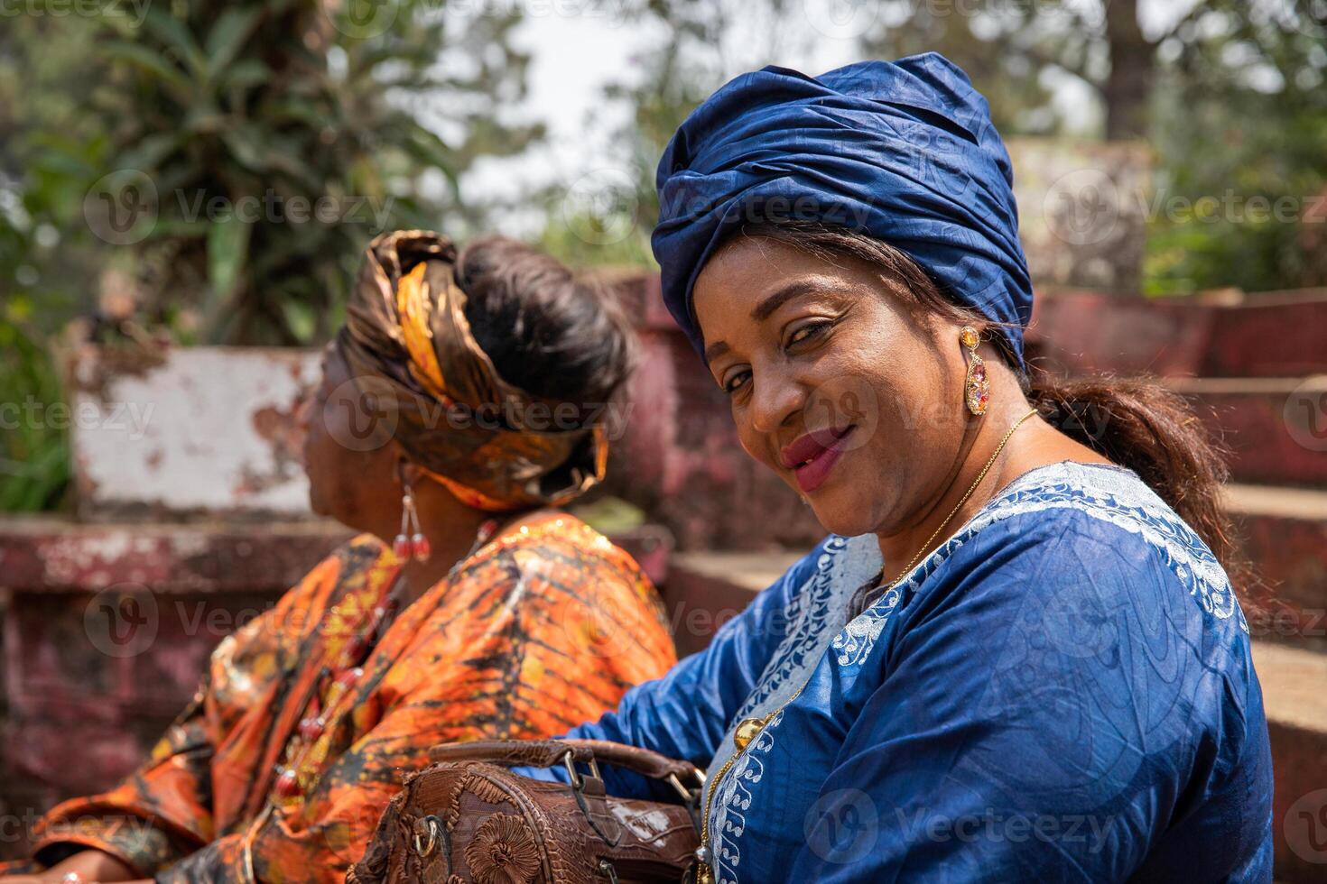Portrait of a smiling African lady dressed in traditional clothes next to a friend. photo