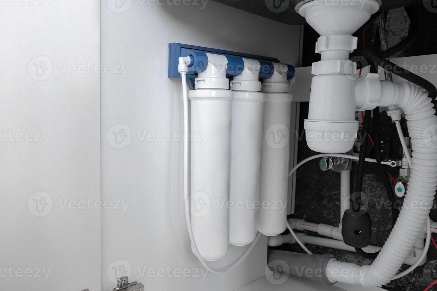 flow-through three-stage purifying water filtration system under the kitchen sink on kitchen photo