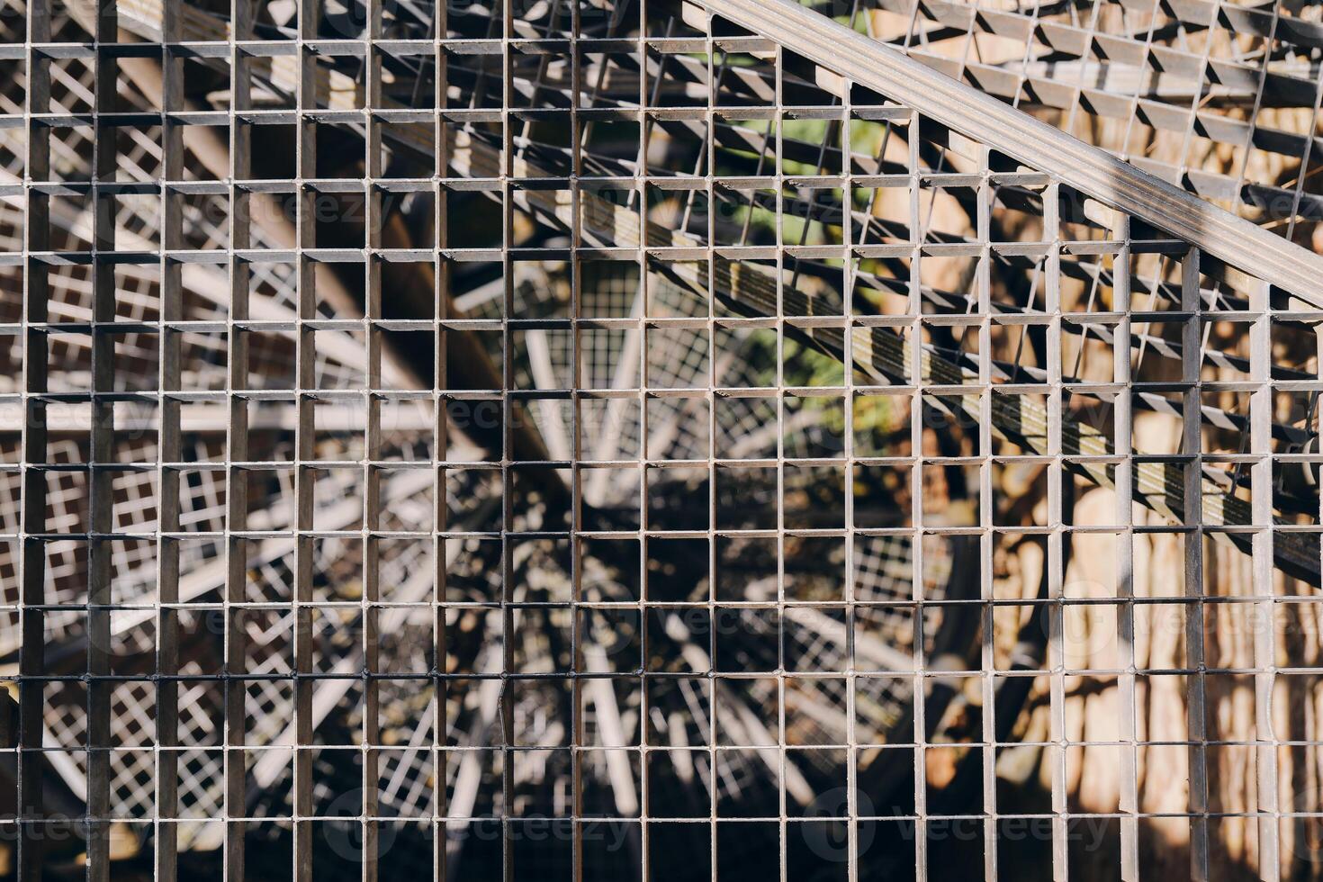 Intricate patterns of light and shadow dance through a woven metal grid on a sunny afternoon in an urban garden oasis photo