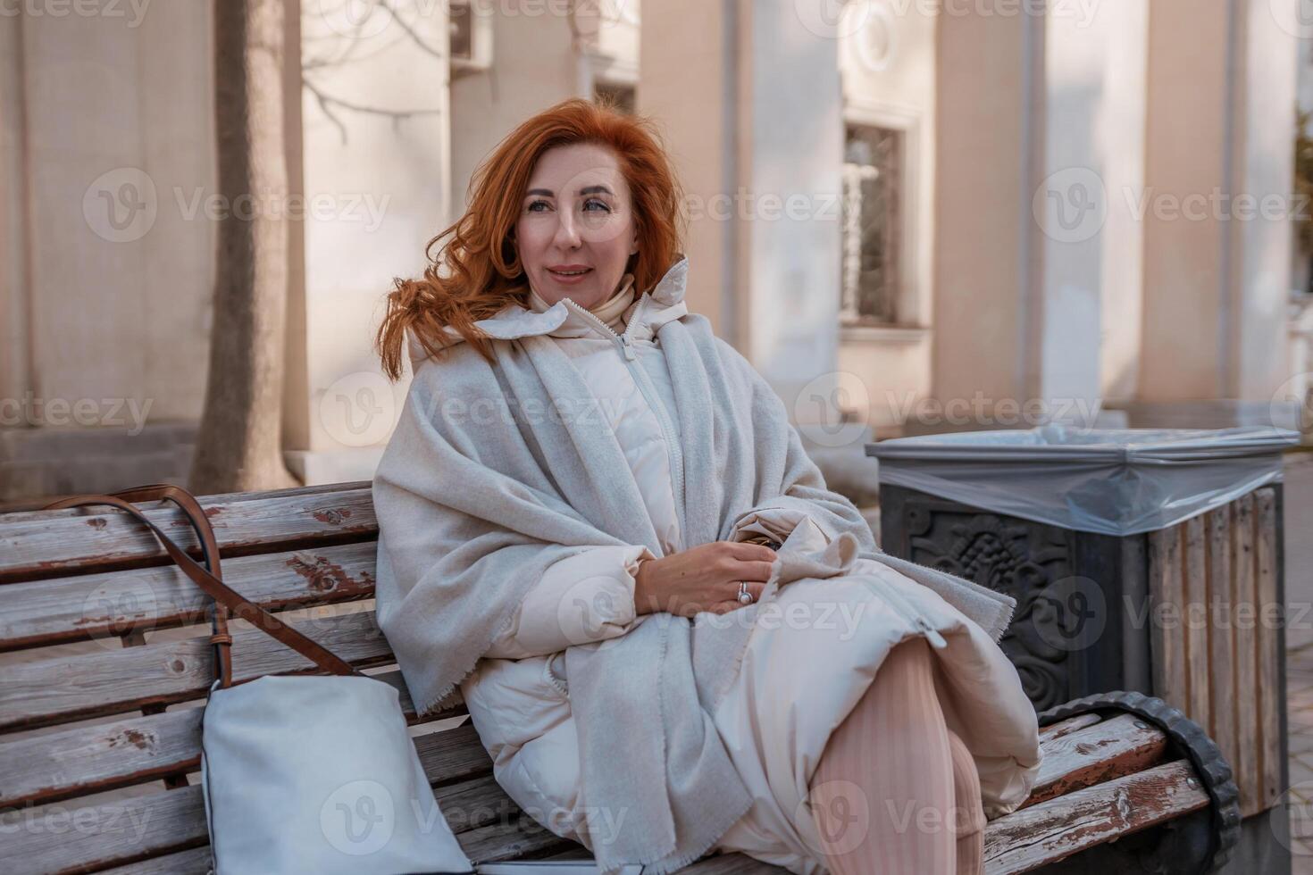 Woman Beige Coat Park Bench. Outdoor autumn portrait, stylish woman relaxes on bench, city setting. photo