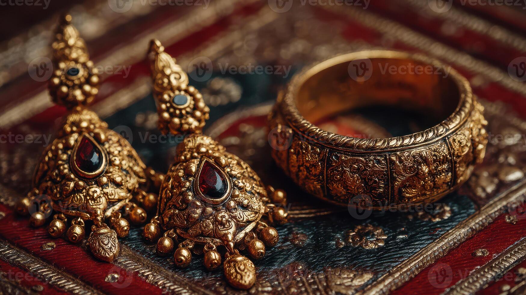 Intricate gold jewelry set featuring ornate earrings and bangle displayed on traditional fabric photo