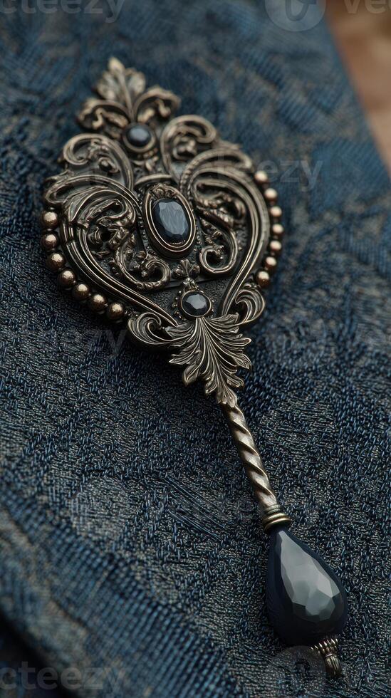Silver decorative spoon with intricate designs and dark gemstones resting on textured blue fabric photo