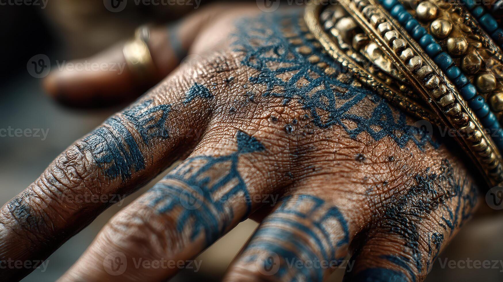 Intricate blue tribal tattoos adorn a hand with decorative bangles in a detailed close-up shot photo