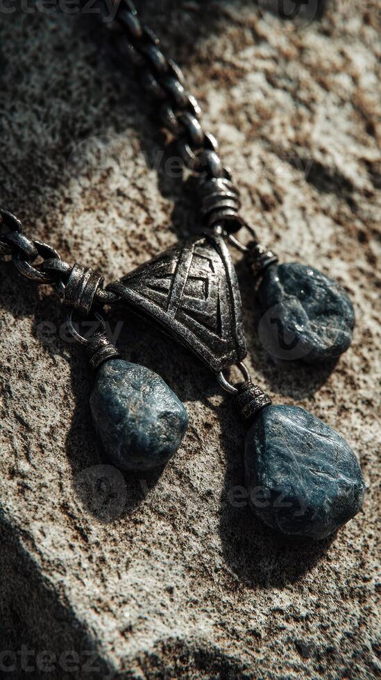 Unique silver necklace with blue stones displayed on textured stone background during soft natural light photo