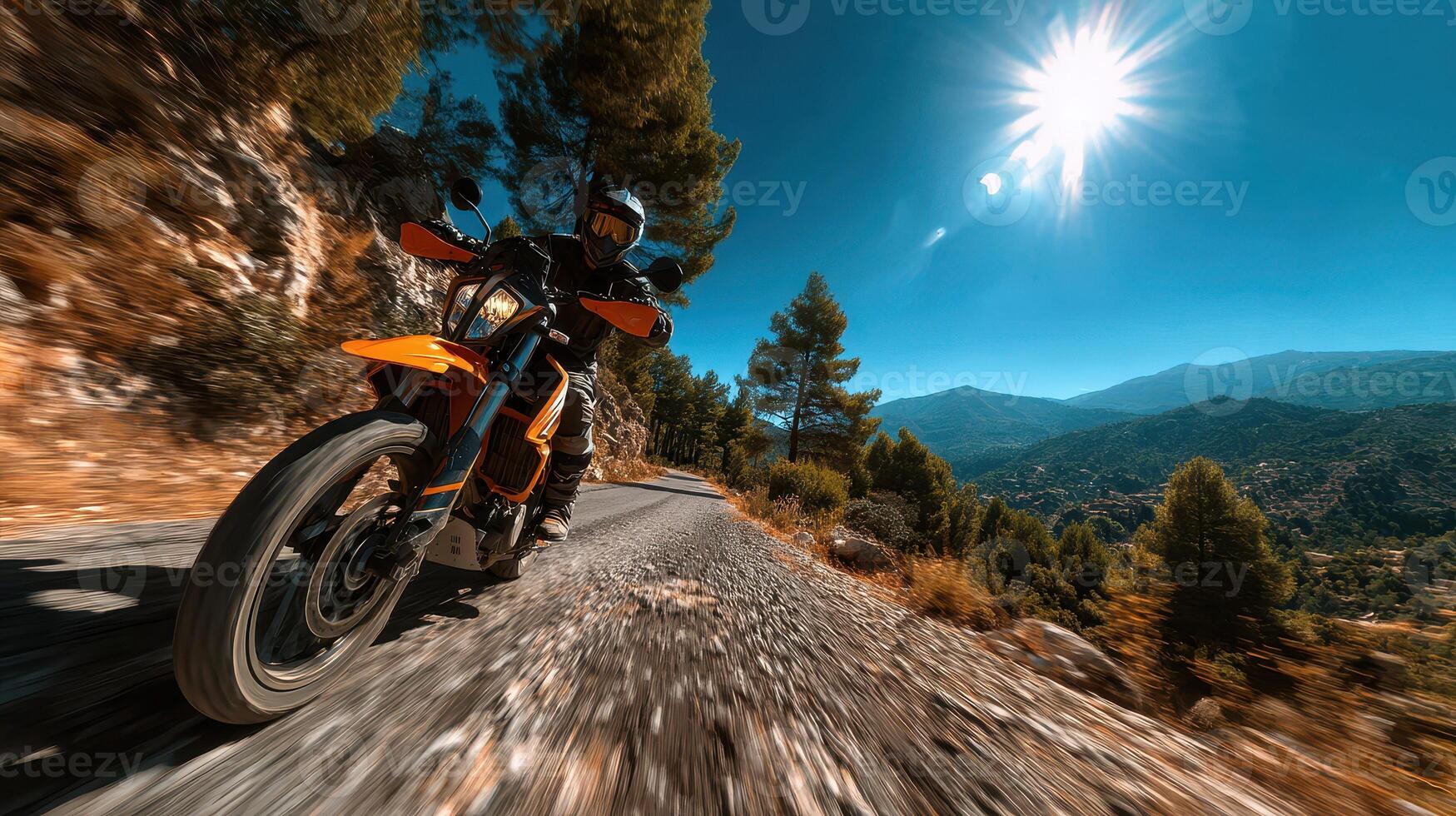 Motorcycle rider navigating a winding mountain road under a bright sun on a clear day in a serene landscape photo
