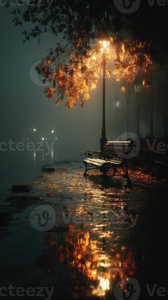 Misty night by the river with a lamp illuminating a bench and reflections on the water photo