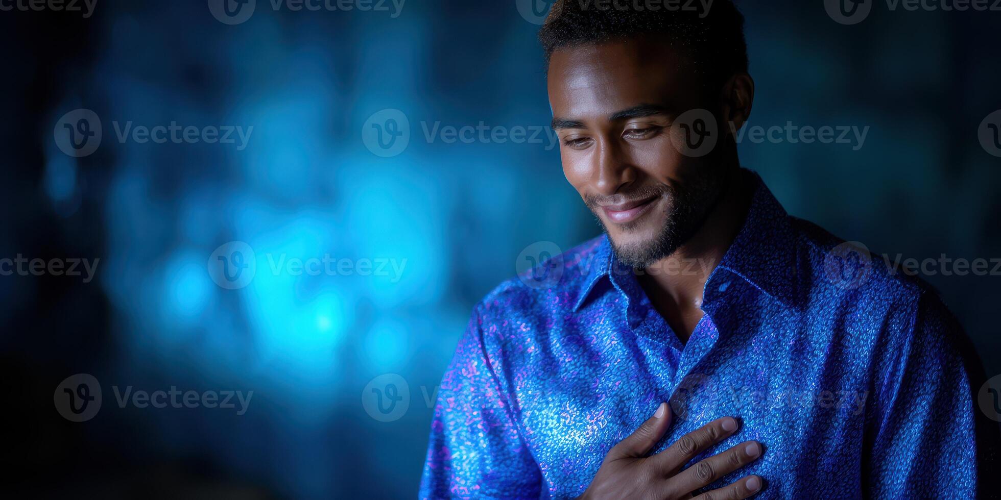 Man in blue patterned shirt smiles warmly in softly illuminated setting during evening gathering photo