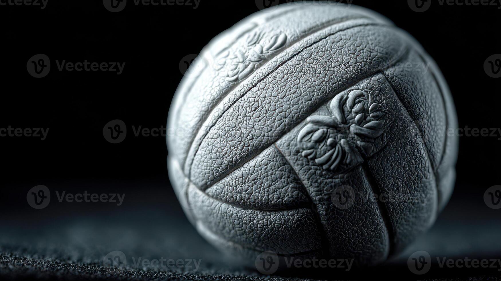 Unique textured gray ball resting on dark surface, showcasing intricate design details in low-light setting photo
