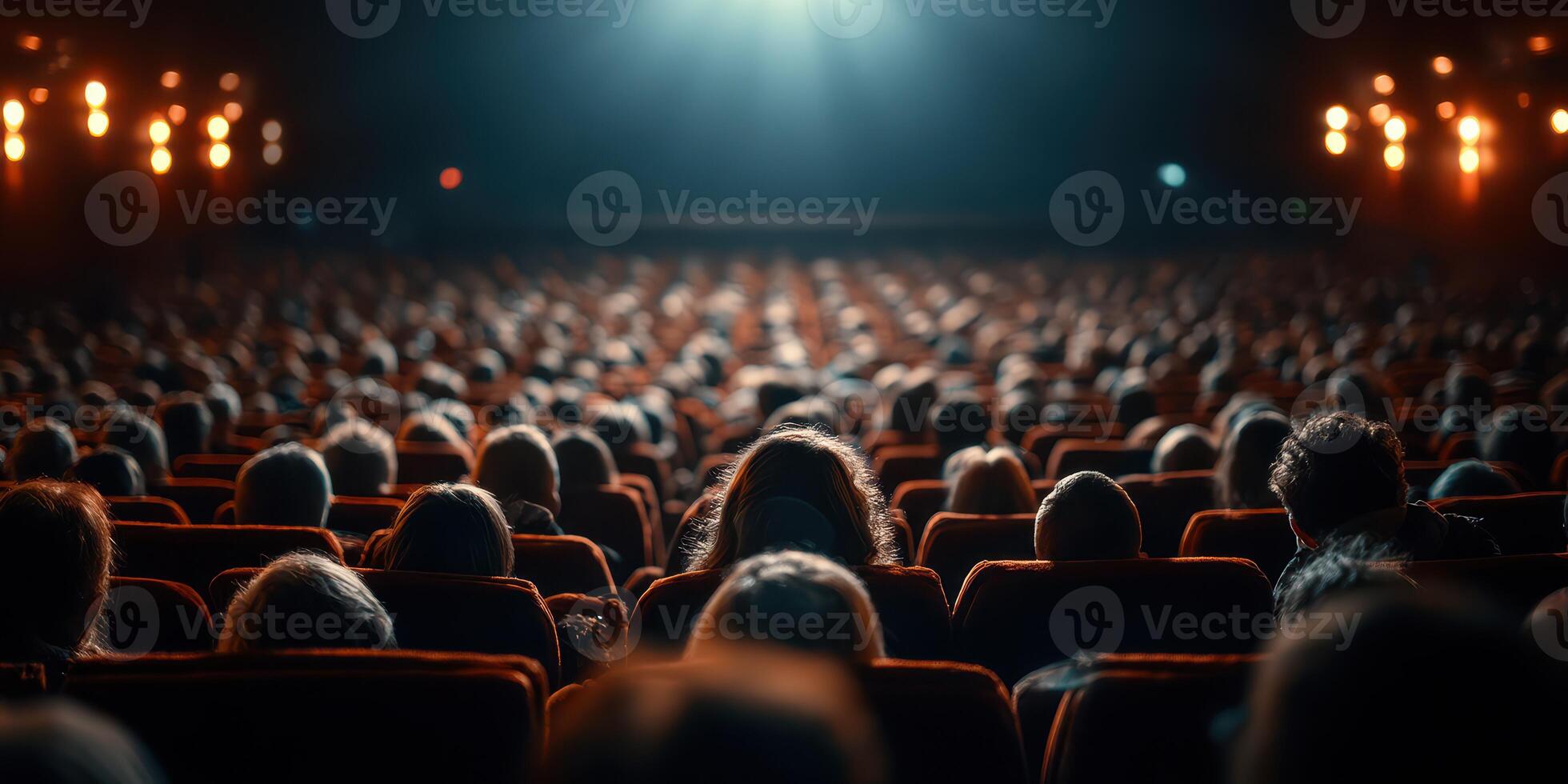 Large audience enjoying a film at a theater during a nighttime screening photo