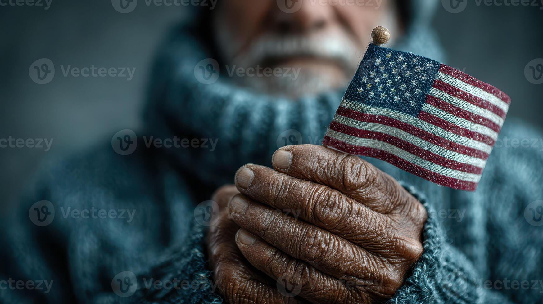 Elderly man holding a small American flag in his hands, showcasing pride and patriotism in a cozy setting photo