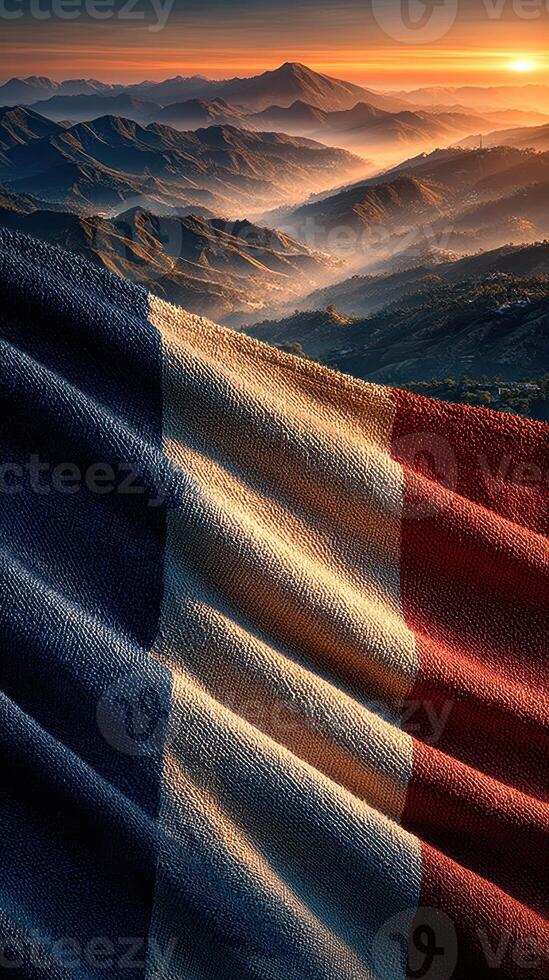Beautiful French flag waving above majestic mountains during a breathtaking sunset photo