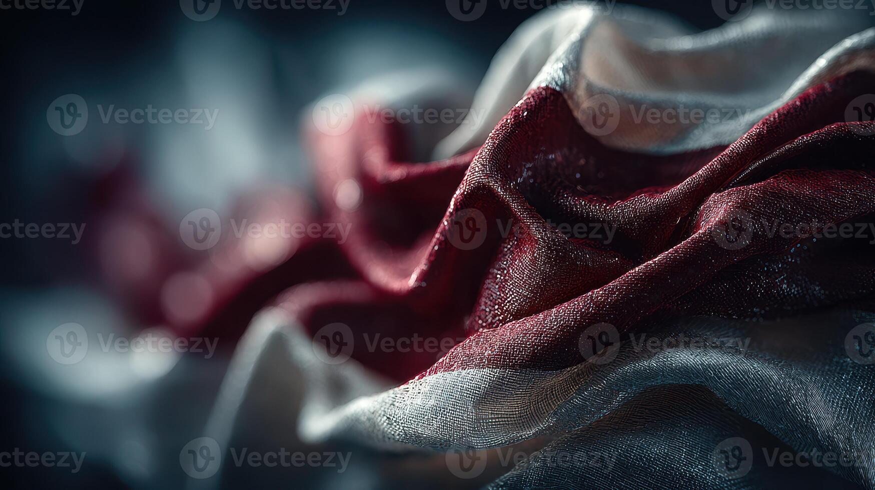 Fabric with red and white folds reflects light creating an artistic abstract design in a dark setting photo
