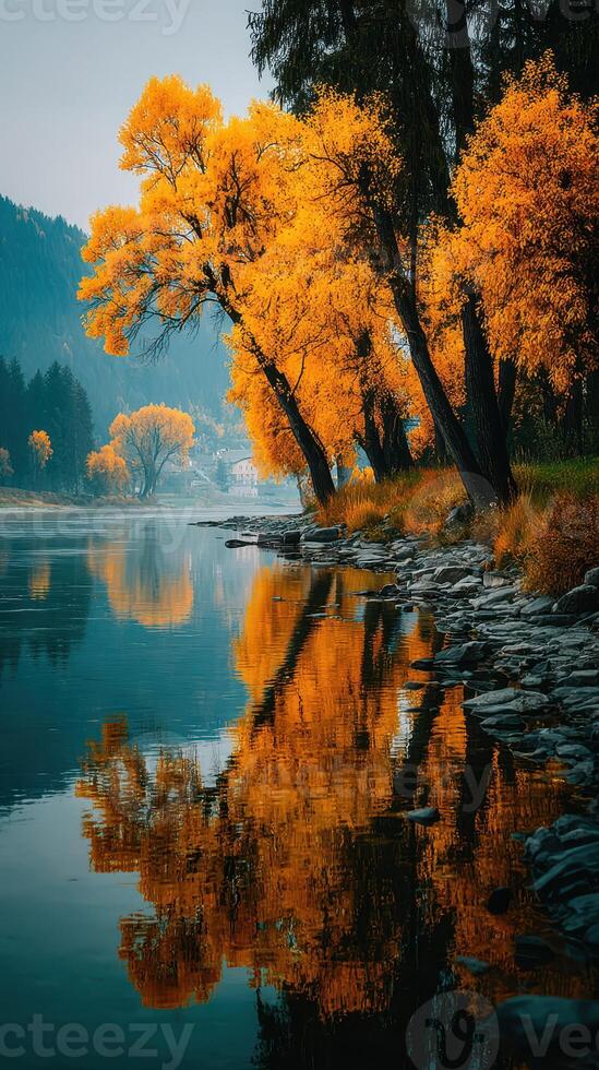 Vibrant autumn foliage reflecting in calm river water surrounded by mountains in a serene natural setting at sunset photo