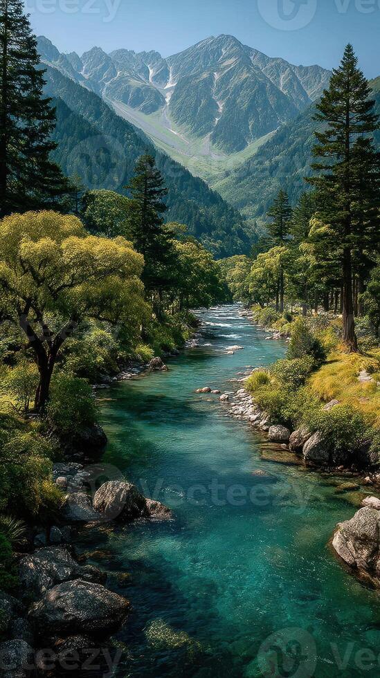 Serene river flowing through lush green forest with majestic mountains in the background on a clear sunny day photo