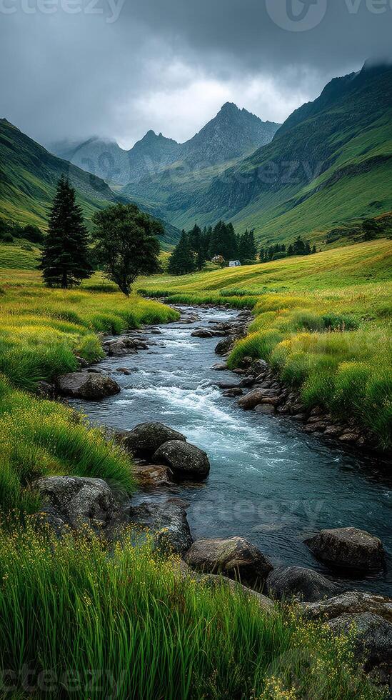 Scenic view of a tranquil river flowing through lush green meadows with mountains in the background on a cloudy day photo