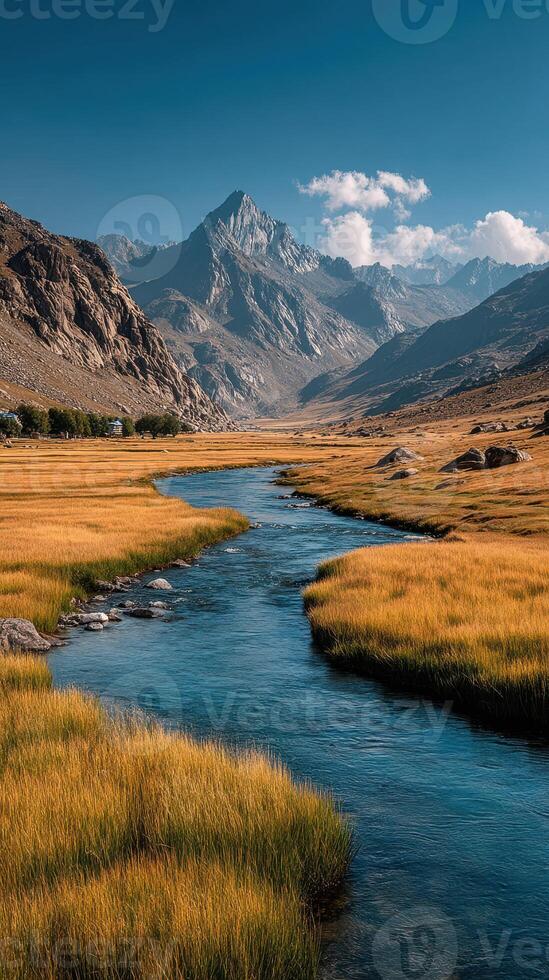 Majestic mountains and serene river flow through golden grasslands under a clear blue sky in the highlands photo