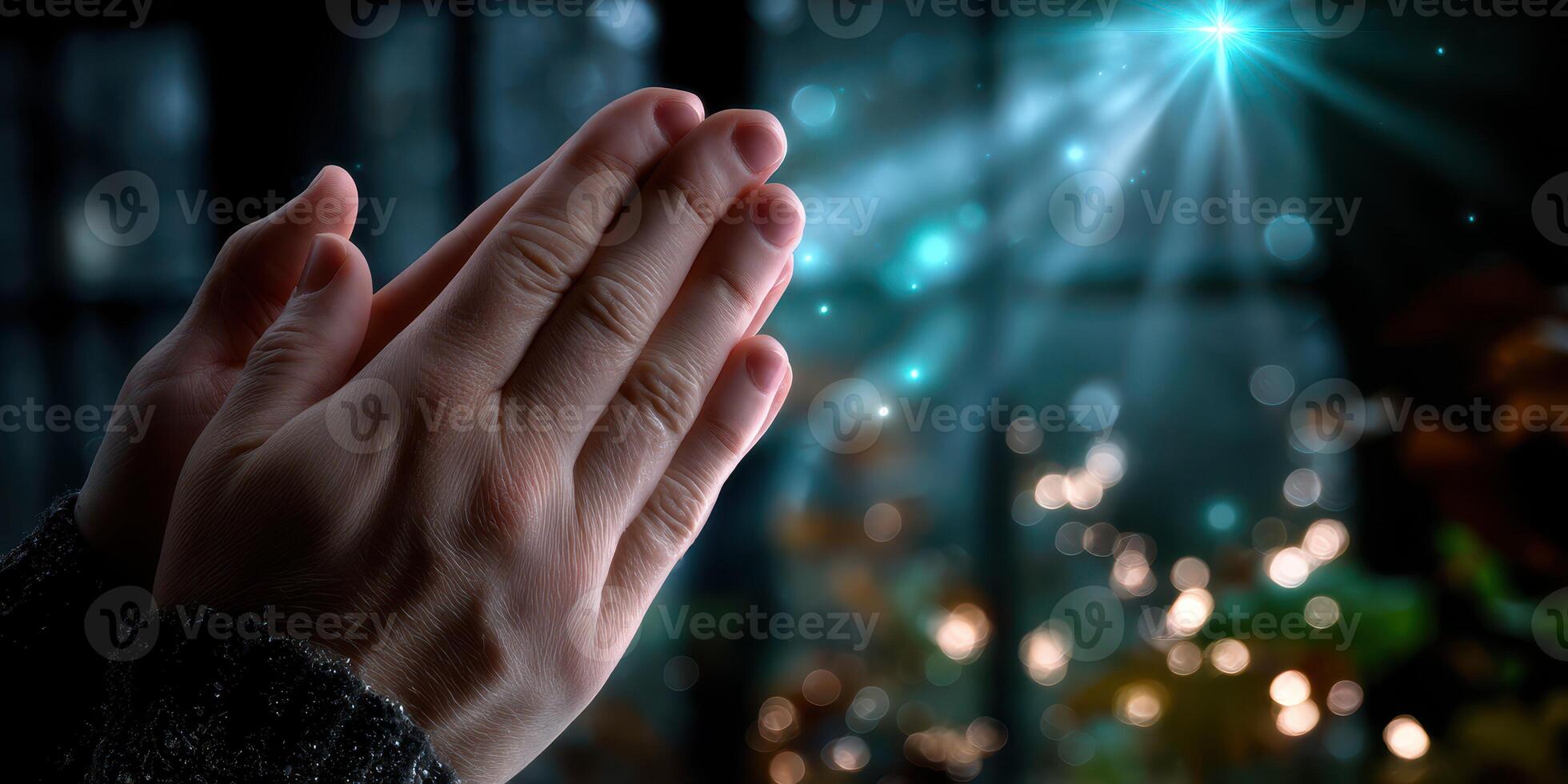 Hands are clasped together in a peaceful gesture, illuminated by soft light filtering through a dark background photo