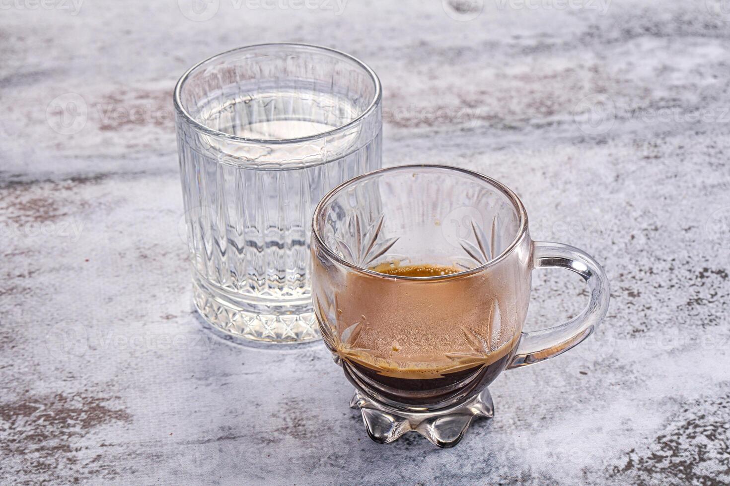 A glass of water next to a glass of coffee photo