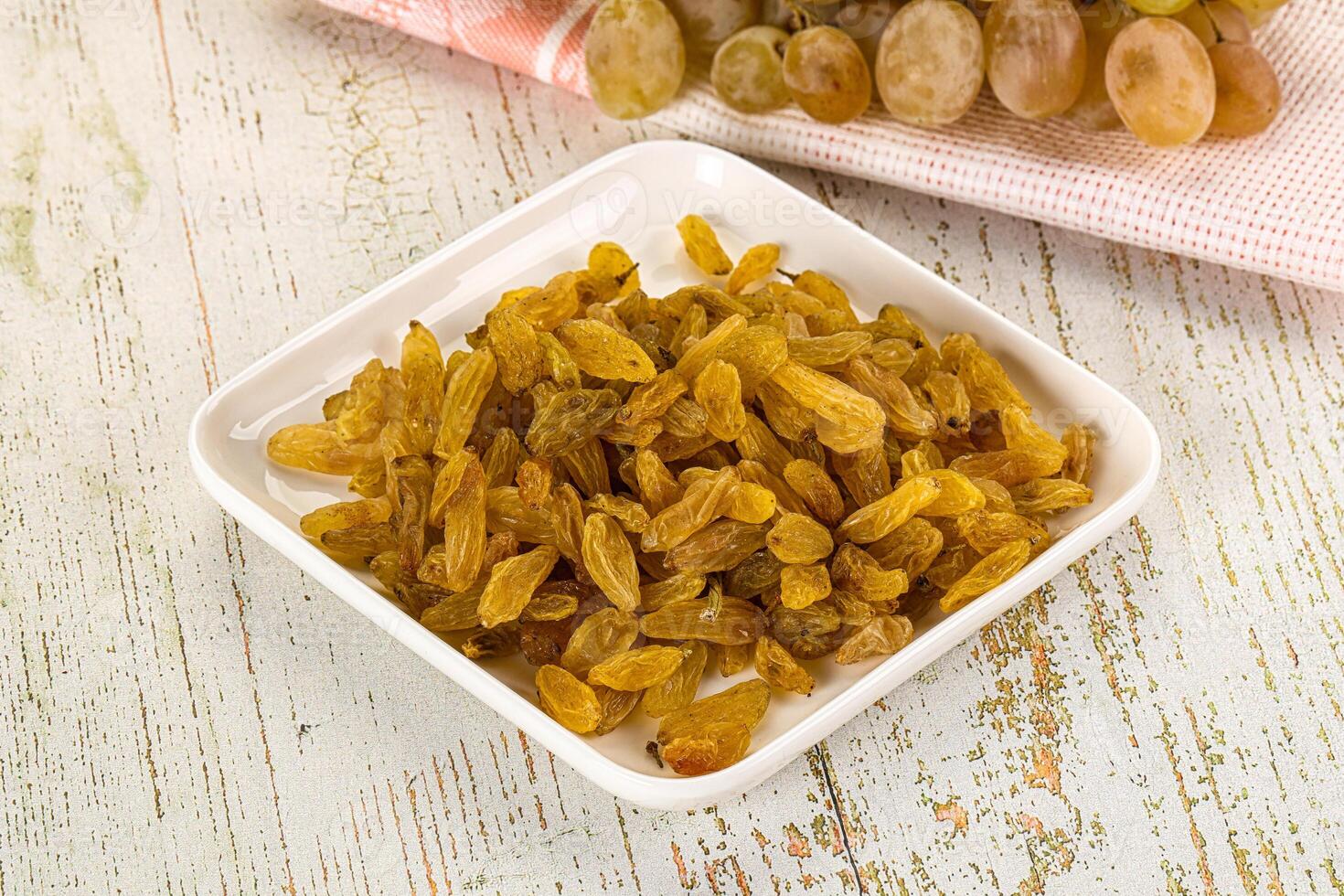 A bowl of dried grapes and a bowl of grapes photo