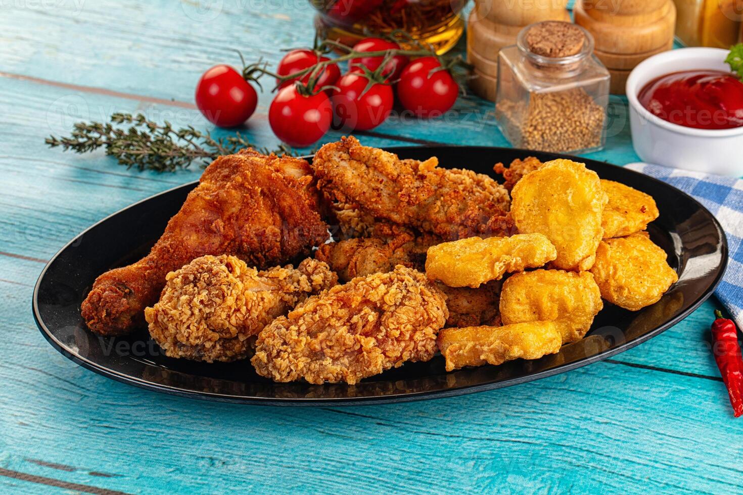 A plate of fried chicken, corn on the cob, and other food photo