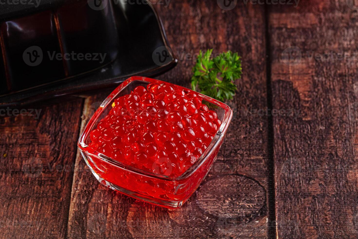A glass of red caviar on a wooden table photo