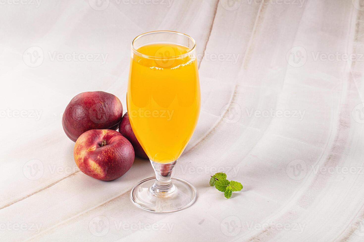 A glass of orange juice and a peach photo