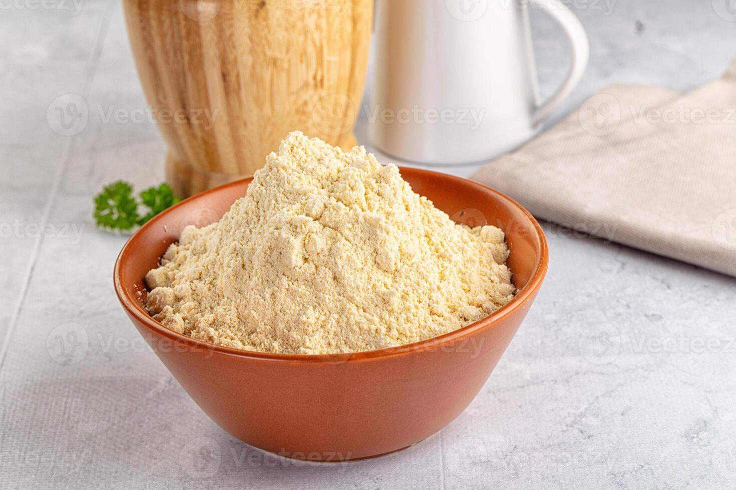 A bowl of flour next to a wooden bowl photo