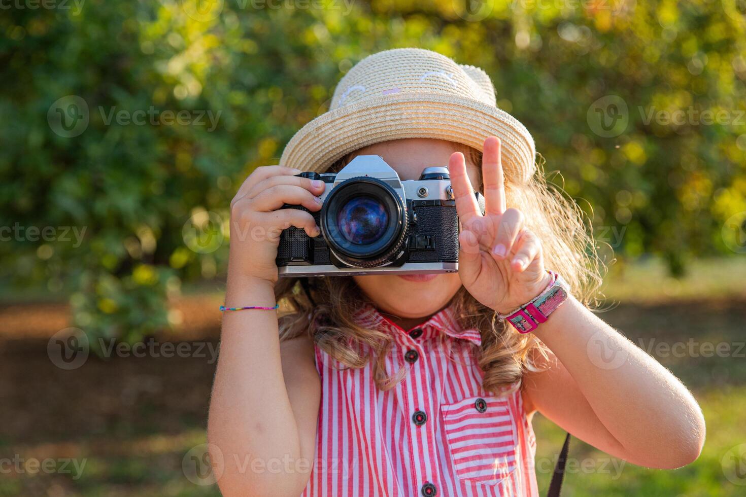 A little girl with a camera takes pictures and makes the V sign with her fingers, photographer concept. photo