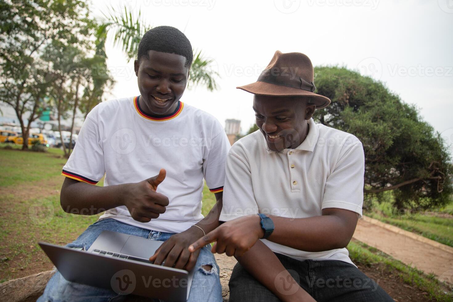 Two students study together using laptop in Africa at a public park photo