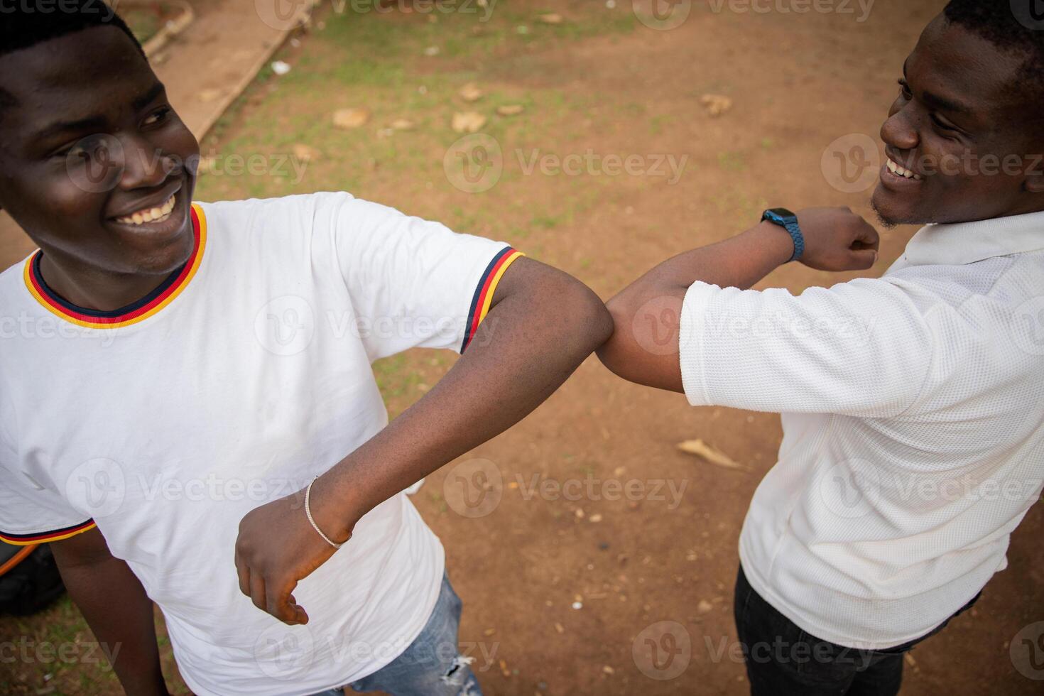 Two friends in africa greeting each other with elbows to reduce contact during coronavirus pandemic, new normal concept. photo