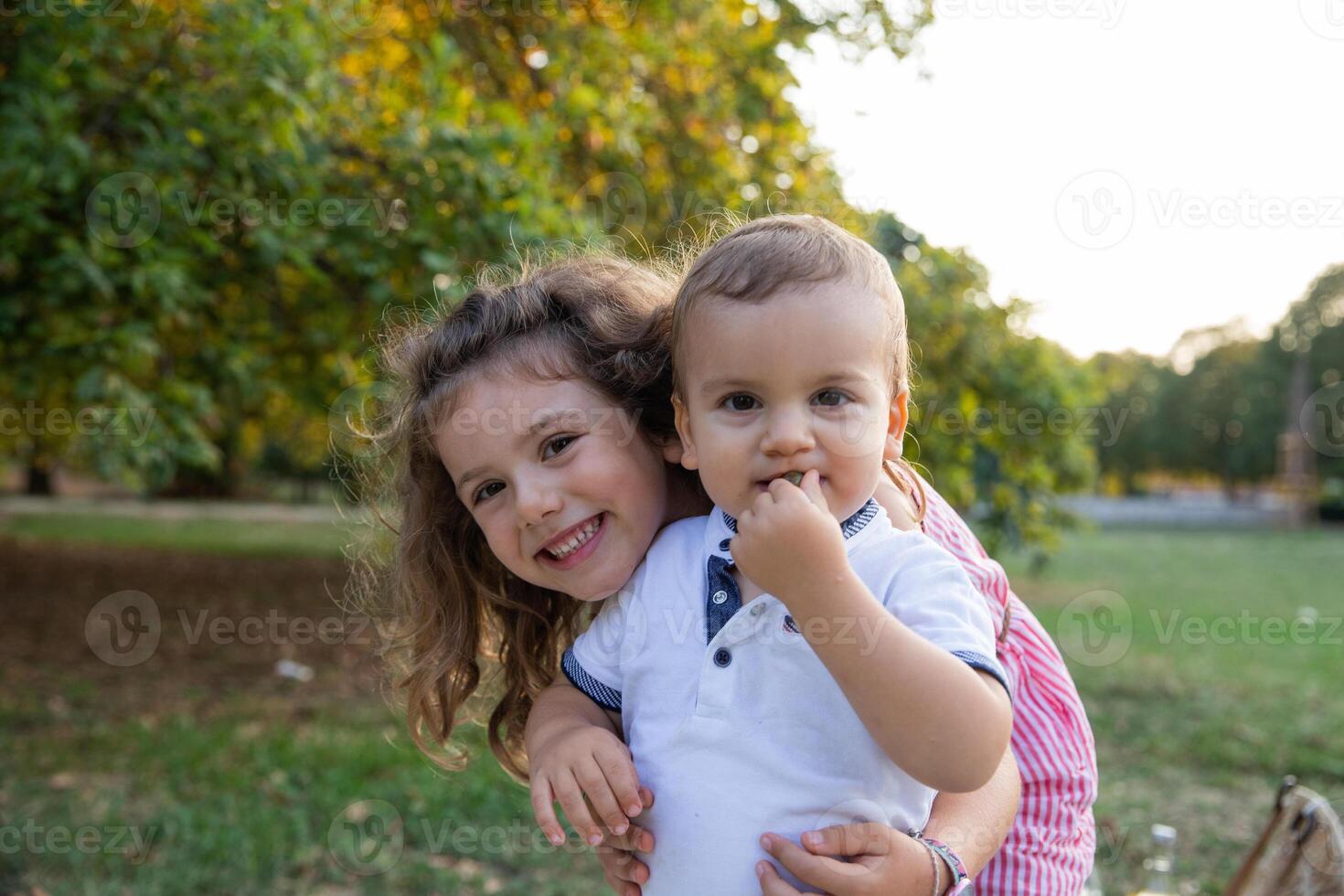 Portrait of brother and sister embracing in a park in the open air, concept of family love. photo