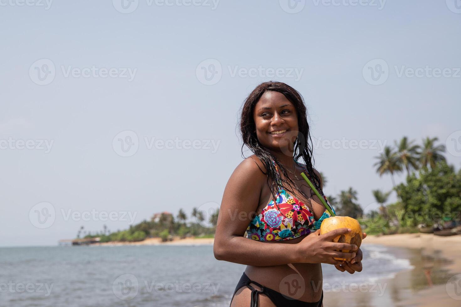 Pretty black girl at the beach during her vacation ready to drink coconut milk photo