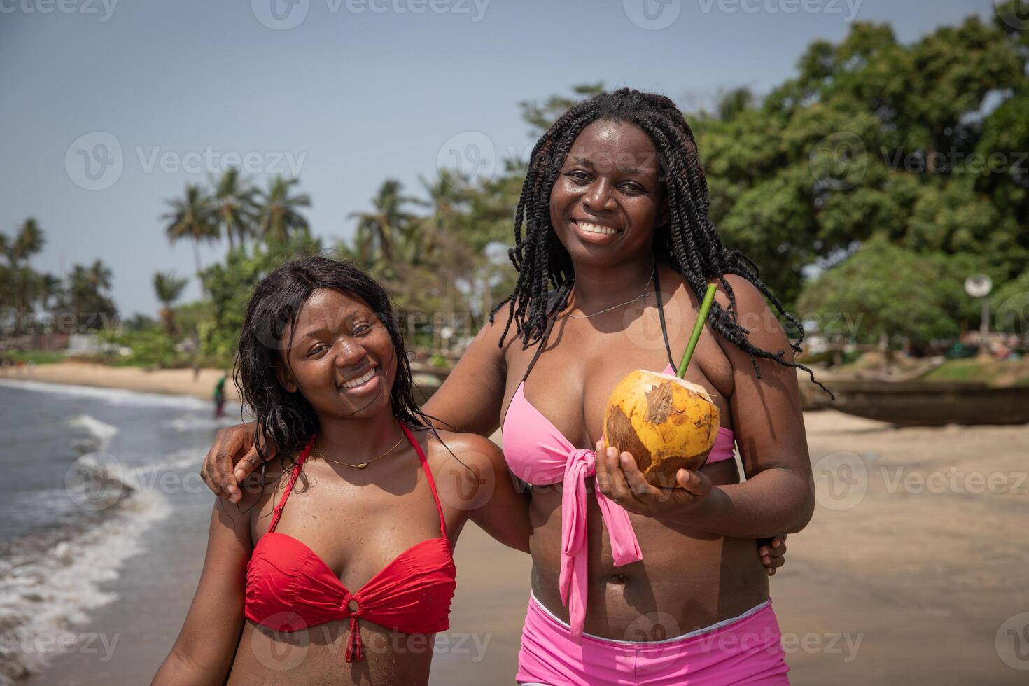 Two young african girls friends on vacation at the natural beach enjoying themselves photo