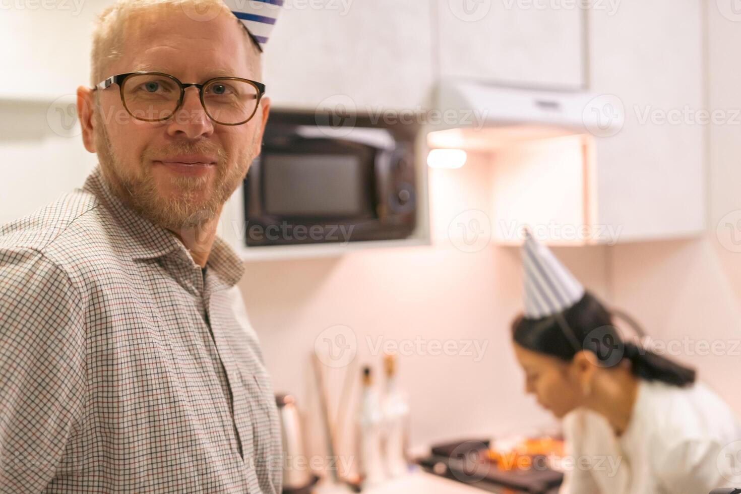 Chef Man Kitchen Cooking. Middle-aged man smiles near chef preparing food in modern kitchen. Event possibly culinary class or demonstration. photo