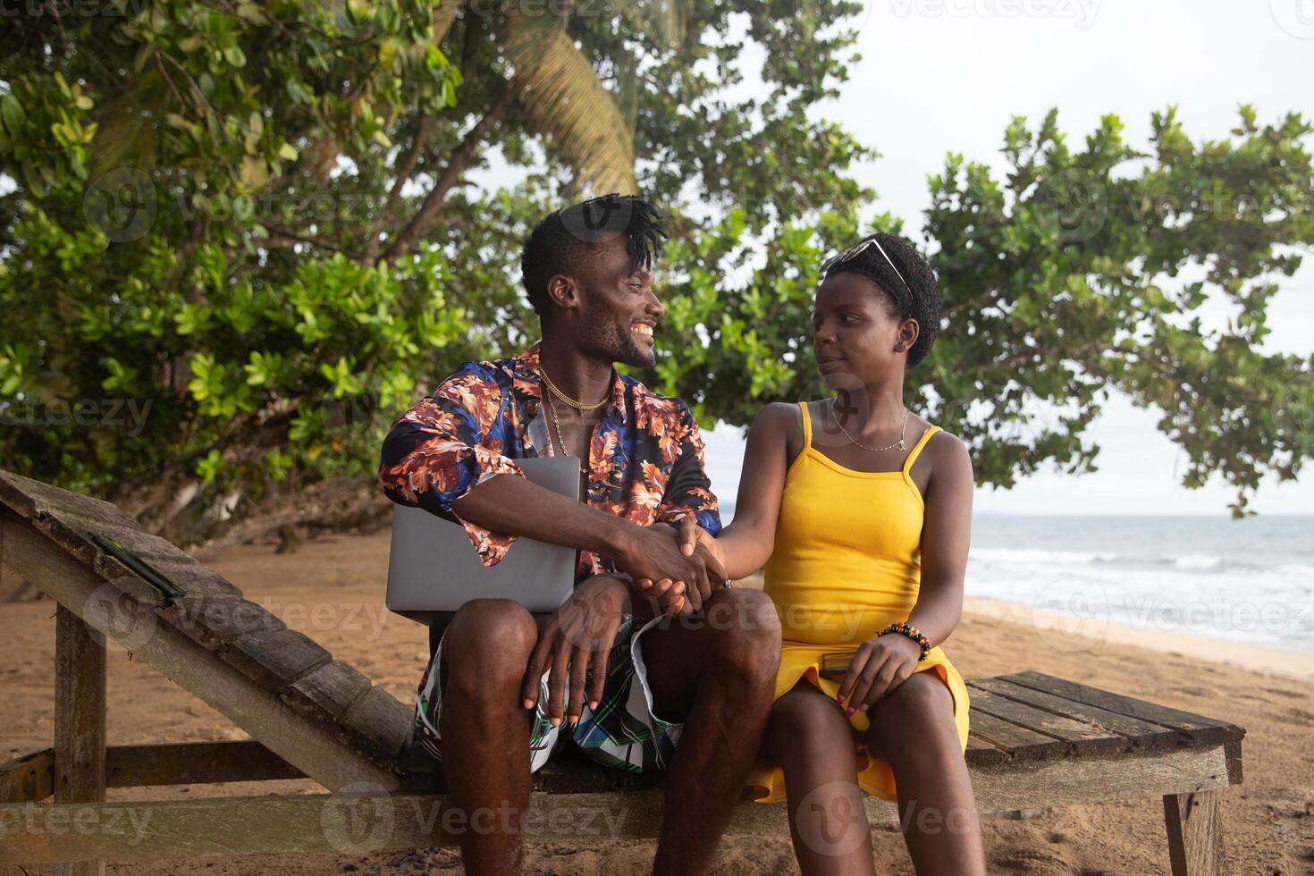 Two digital nomad friends sitting on the bench by the sea shake hands photo