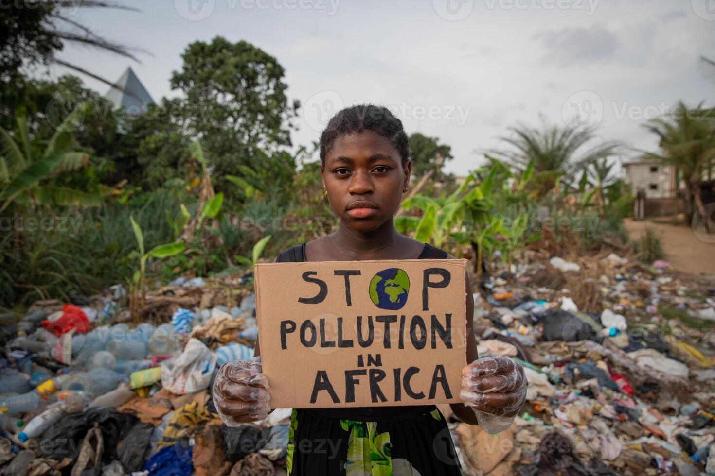 Young black african girl holding a sign written stop pollution in Africa photo