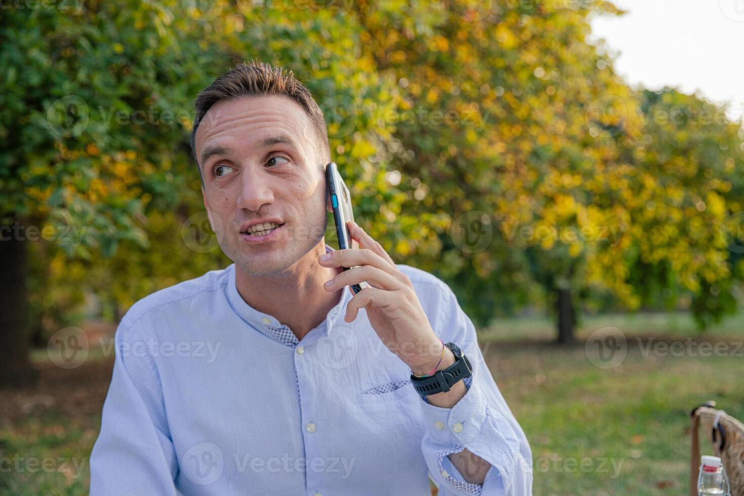 A man is having a phone call outdoor, person talking to somebody through the phone. photo