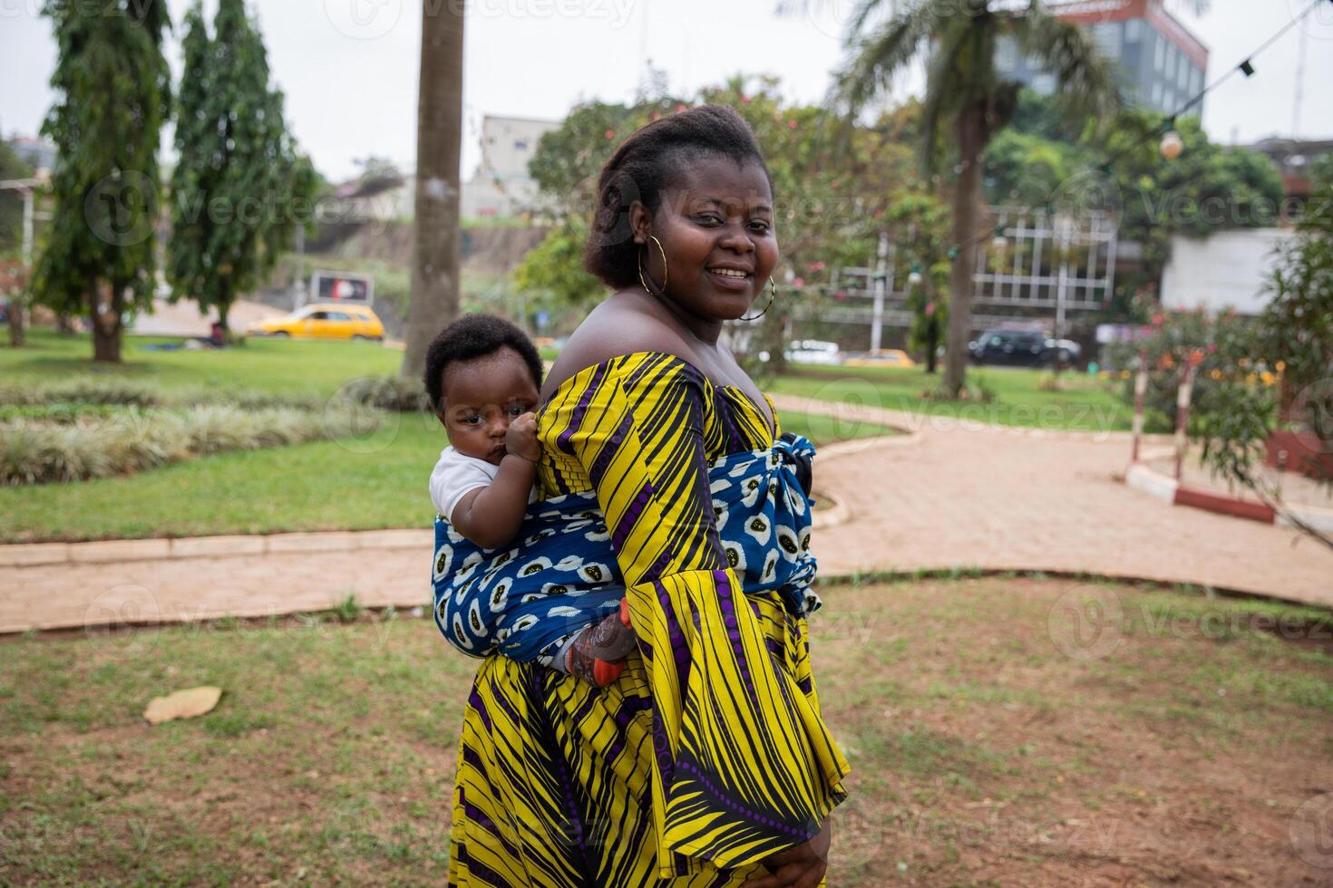 Portrait of an African mother holding her son tied on her back with a headscarf photo