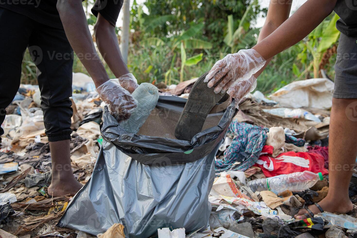 Close-up of the hands of two african guys collecting rubbish left on the street with a garbage bag, africa environmental care concept. photo